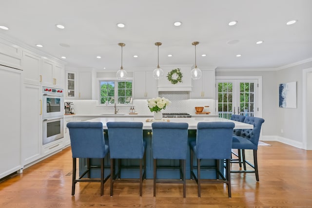 25 Conrad Rd, New Canaan, CT 06840 - kitchen with double oven, plenty of natural light, white cabinetry, a center island, and crown molding