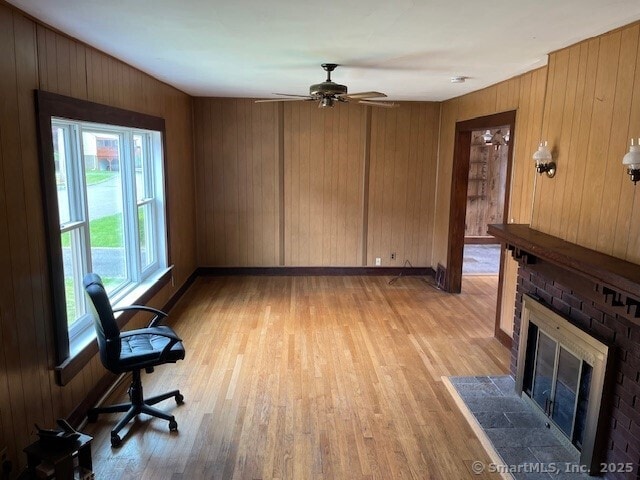 79 Van St, Stratford, CT 06614 - unfurnished living room with a fireplace, light wood-style floors, ceiling fan, wooden walls, and baseboards