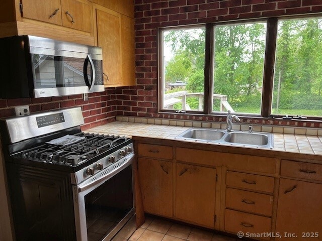 79 Van St, Stratford, CT 06614 - kitchen featuring appliances with stainless steel finishes, tile counters, a sink, decorative backsplash, and light tile patterned floors