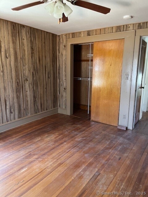 79 Van St, Stratford, CT 06614 - unfurnished bedroom featuring a closet, wood finished floors, wood walls, and a ceiling fan