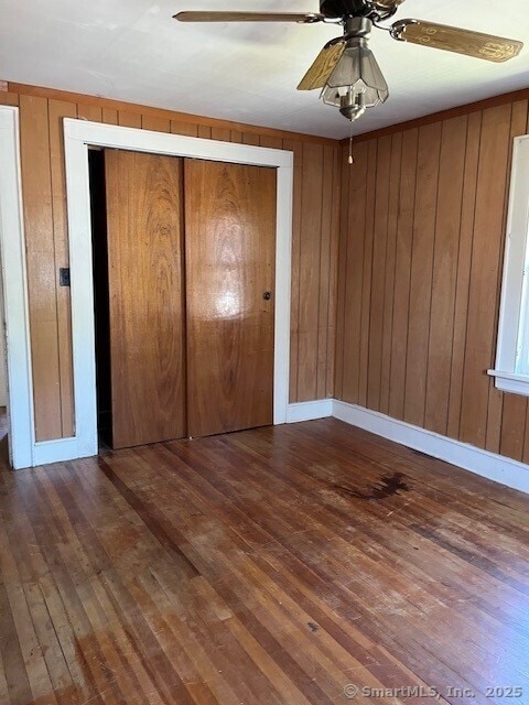 79 Van St, Stratford, CT 06614 - unfurnished bedroom with hardwood / wood-style flooring, wood walls, a ceiling fan, and a closet