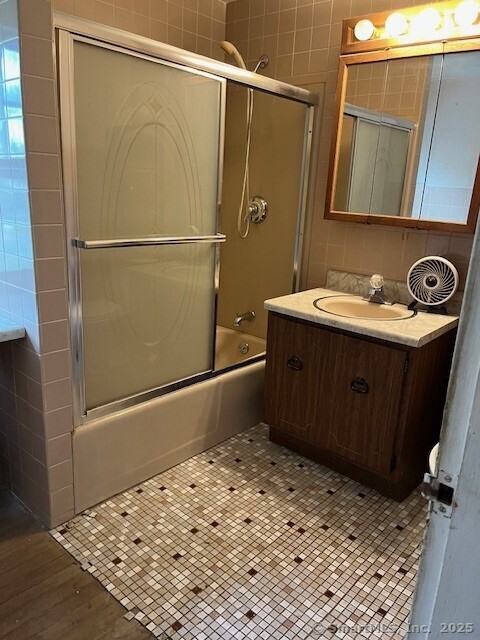 79 Van St, Stratford, CT 06614 - full bathroom featuring vanity, tile walls, and combined bath / shower with glass door