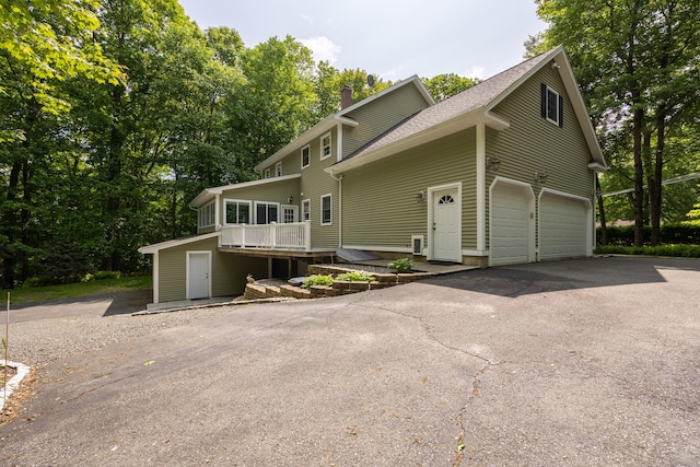 155 Garrigus Ct, Wolcott, CT 06716 - view of front facade with driveway, a chimney, a wooden deck, and an attached garage