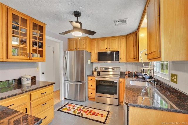 41 Blueberry Cir, Ellington, CT 06029 - kitchen featuring stainless steel appliances, a sink, a ceiling fan, dark stone countertops, and glass insert cabinets