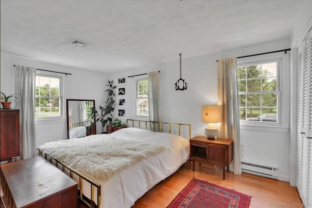 41 Blueberry Cir, Ellington, CT 06029 - bedroom featuring a baseboard heating unit, multiple windows, light wood finished floors, and a textured ceiling
