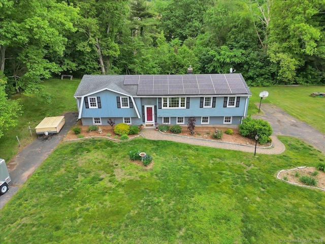 41 Blueberry Cir, Ellington, CT 06029 - split foyer home with driveway, a front lawn, solar panels, a forest view, and roof with shingles