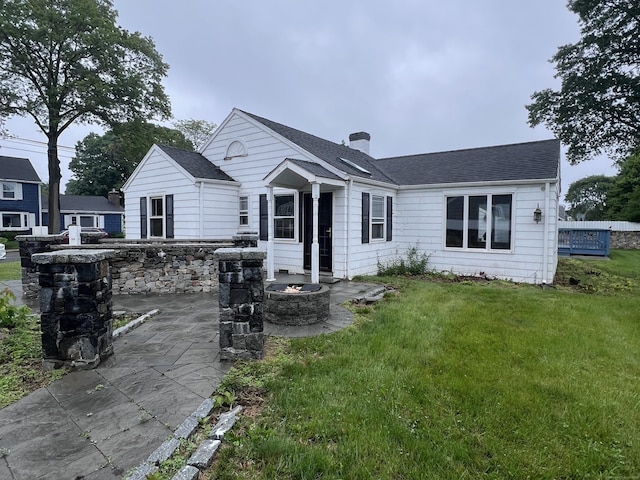 39 Commodore Pl, Milford, CT 06460 - back of property with a lawn, a patio area, an outdoor fire pit, a chimney, and roof with shingles