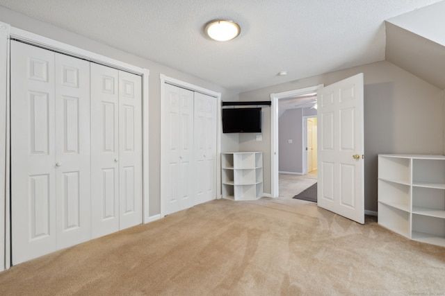 21 Dilaj Dr, Columbia, CT 06237 - unfurnished bedroom featuring multiple closets, light colored carpet, a textured ceiling, and vaulted ceiling