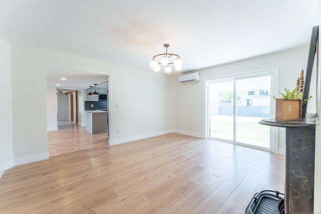 369 Thompson Rd, Thompson, CT 06277 - unfurnished living room featuring a wall unit AC, a chandelier, light wood finished floors, and baseboards