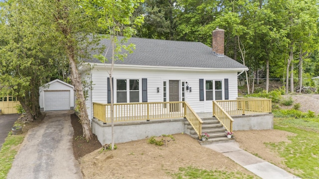 452 New Haven Ave, Derby, CT 06418 - view of front facade featuring an outbuilding, asphalt driveway, a chimney, a detached garage, and a shingled roof