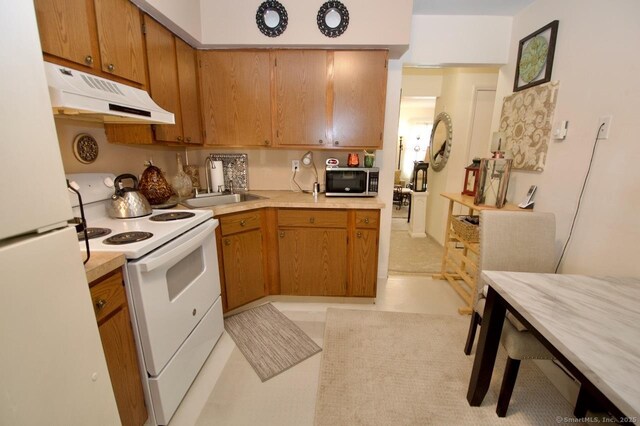 35 Mountain Village Rd Unit 15, Waterbury, CT 06706 - kitchen with white appliances, under cabinet range hood, light countertops, a sink, and brown cabinetry