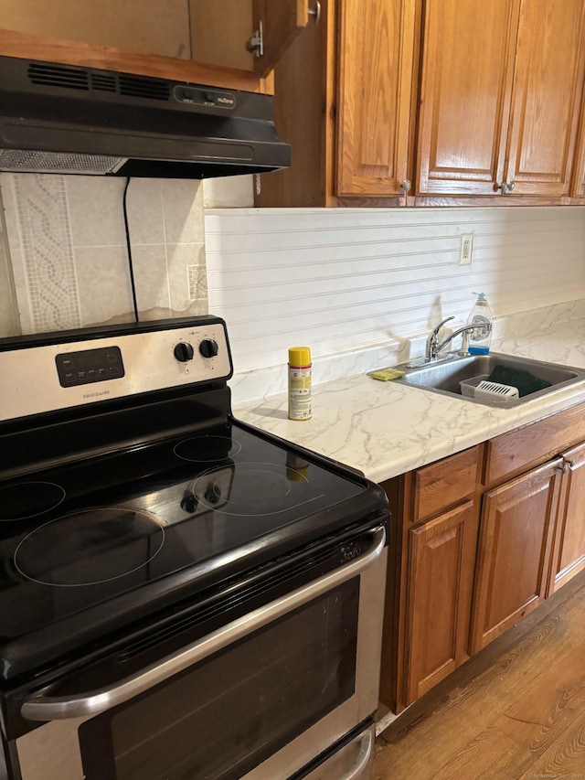 70 W St, New London, CT 06320 - kitchen featuring electric range, a sink, under cabinet range hood, and brown cabinetry