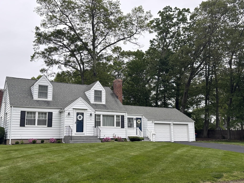 110 Cottage St, Trumbull, CT 06611 - new england style home featuring a garage, asphalt driveway, a chimney, a shingled roof, and entry steps