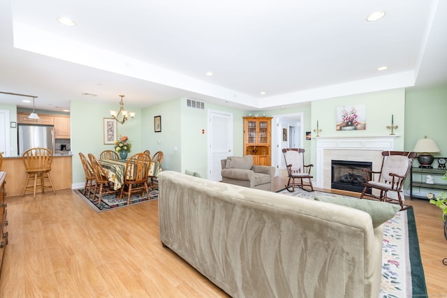 237 Fern St Apt 206W, West Hartford, CT 06119 - living area featuring a fireplace, light wood-type flooring, a tray ceiling, recessed lighting, and a chandelier