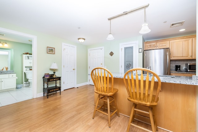 237 Fern St Apt 206W, West Hartford, CT 06119 - kitchen with appliances with stainless steel finishes, a breakfast bar area, light stone countertops, light wood-style flooring, and decorative light fixtures