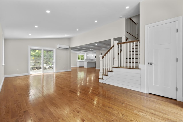 73 Nedobity Rd, Haddam, CT 06441 - unfurnished living room with a wall mounted air conditioner, stairway, wood finished floors, baseboards, and recessed lighting