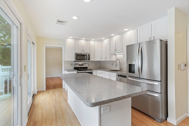 31 Elizabeth St, Shelton, CT 06484 - kitchen with appliances with stainless steel finishes, a sink, white cabinets, light wood-style flooring, and tasteful backsplash