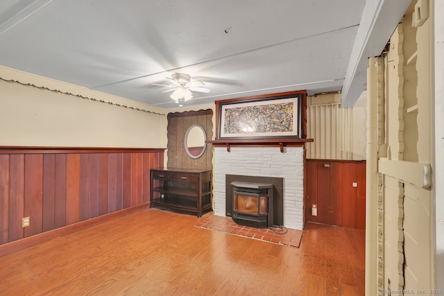 38 Craig Ave, Southington, CT 06489 - unfurnished living room featuring a wood stove, ceiling fan, wood finished floors, a wainscoted wall, and wood walls