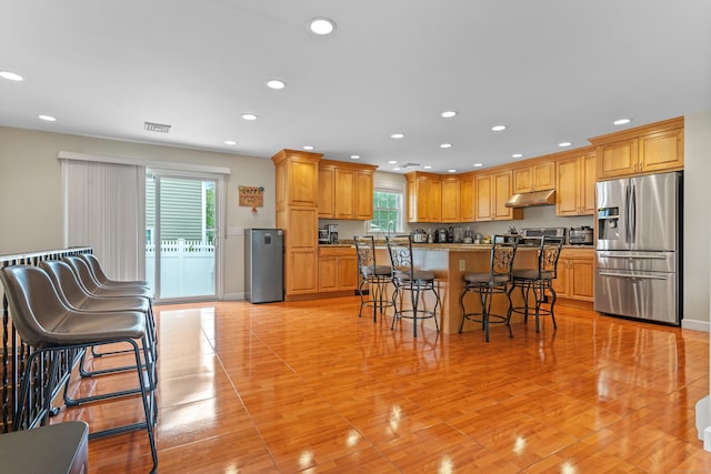 3657 Park Ave, Fairfield, CT 06825 - kitchen with stainless steel refrigerator with ice dispenser, under cabinet range hood, a breakfast bar area, a kitchen island, and recessed lighting
