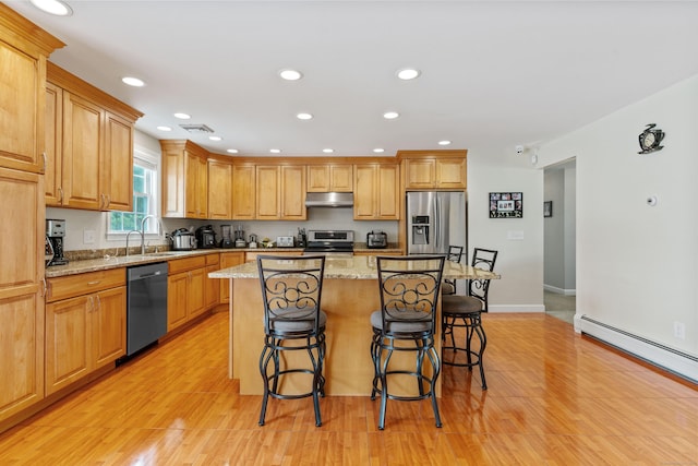 3657 Park Ave, Fairfield, CT 06825 - kitchen with stainless steel appliances, under cabinet range hood, a breakfast bar, a center island, and light wood-style floors