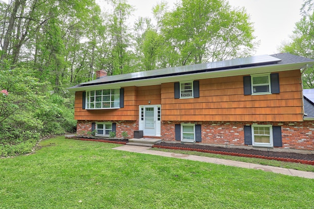 408 Reservoir Rd, Southbury, CT 06488 - bi-level home featuring a front lawn, roof mounted solar panels, a chimney, and brick siding