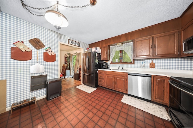 408 Reservoir Rd, Southbury, CT 06488 - kitchen with stainless steel appliances, wallpapered walls, a sink, light countertops, and a textured ceiling