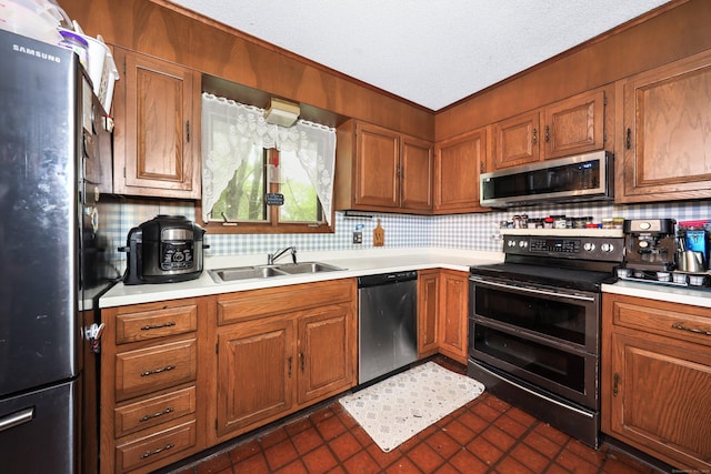 408 Reservoir Rd, Southbury, CT 06488 - kitchen with stainless steel appliances, a sink, light countertops, brown cabinetry, and ornamental molding