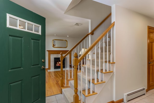 113 Charles St, Tolland, CT 06084 - entrance foyer featuring baseboard heating, tile patterned flooring, a fireplace, and stairs