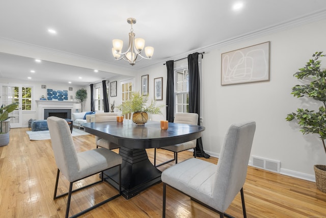 182 5th St, Stamford, CT 06905 - dining area with a chandelier, light wood-type flooring, a fireplace, ornamental molding, and recessed lighting