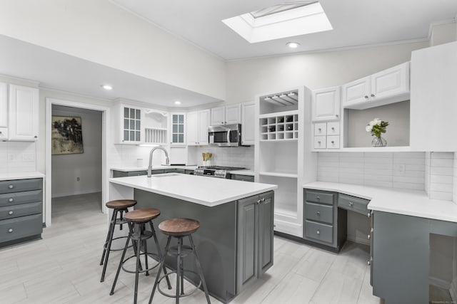 182 5th St, Stamford, CT 06905 - kitchen featuring stainless steel microwave, gray cabinets, a skylight, a sink, and range