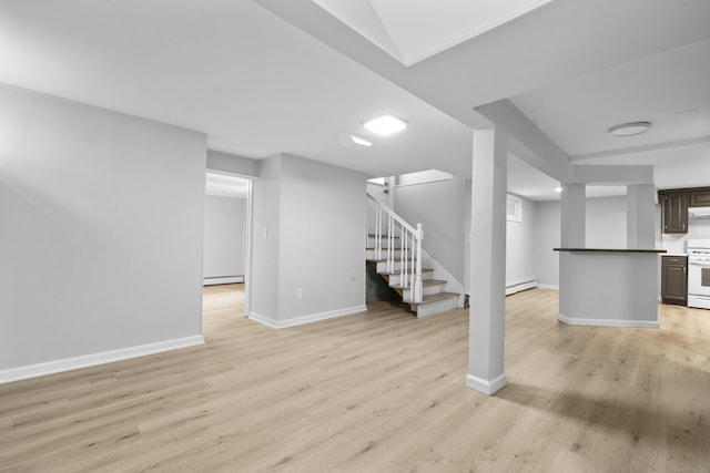 182 5th St, Stamford, CT 06905 - finished below grade area with light wood-style floors, stairs, baseboards, and a baseboard heating unit