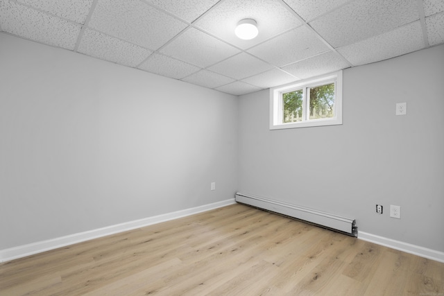 182 5th St, Stamford, CT 06905 - below grade area featuring baseboard heating, a drop ceiling, light wood finished floors, and baseboards
