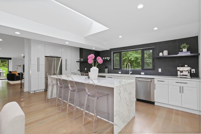 23 Wyndover Ln N, Stamford, CT 06902 - kitchen featuring stainless steel appliances, light wood-style flooring, a sink, a kitchen island, and tasteful backsplash