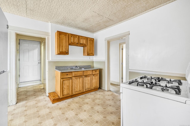 67 Ash St, Bridgeport, CT 06605 - kitchen featuring white gas range oven, brown cabinetry, an ornate ceiling, and light flooring