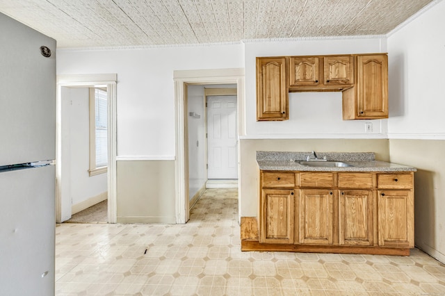 67 Ash St, Bridgeport, CT 06605 - kitchen featuring freestanding refrigerator, ornamental molding, brown cabinets, and light countertops