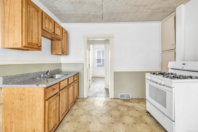67 Ash St, Bridgeport, CT 06605 - kitchen featuring white gas range, an ornate ceiling, light floors, and brown cabinets