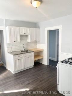 67 Ash St, Bridgeport, CT 06605 - kitchen with gas range gas stove, dark wood-style floors, backsplash, white cabinets, and wainscoting