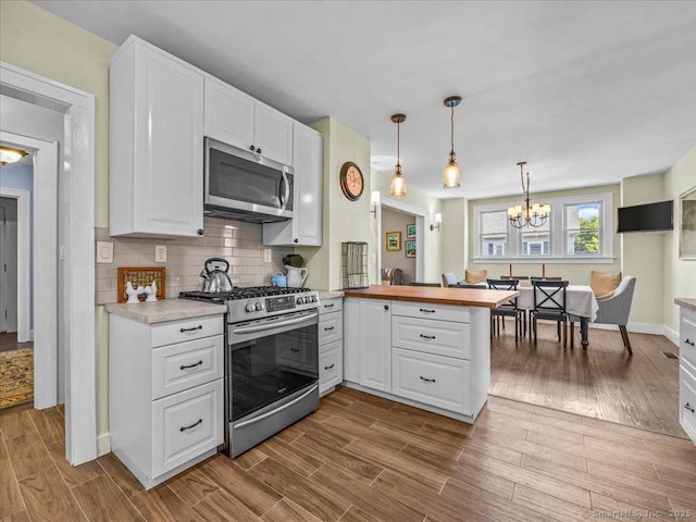 102 Columbus Ave, Meriden, CT 06451 - kitchen with appliances with stainless steel finishes, a peninsula, white cabinetry, and a chandelier