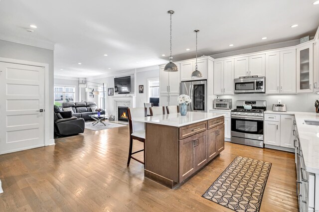 74 Sterling St, Fairfield, CT 06825 - kitchen featuring appliances with stainless steel finishes, a fireplace, a breakfast bar, open floor plan, and wood finished floors