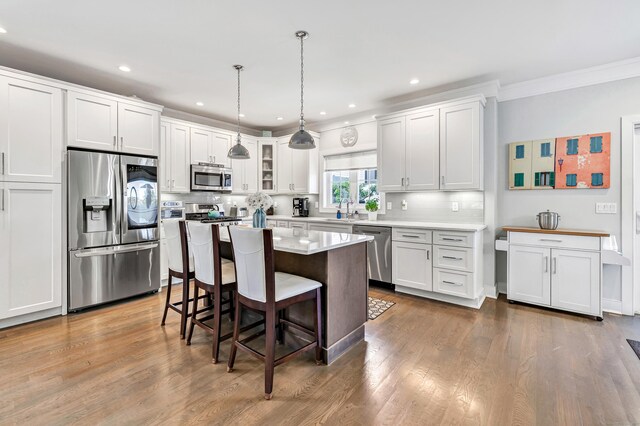 74 Sterling St, Fairfield, CT 06825 - kitchen featuring stainless steel appliances, ornamental molding, a kitchen breakfast bar, decorative backsplash, and glass insert cabinets