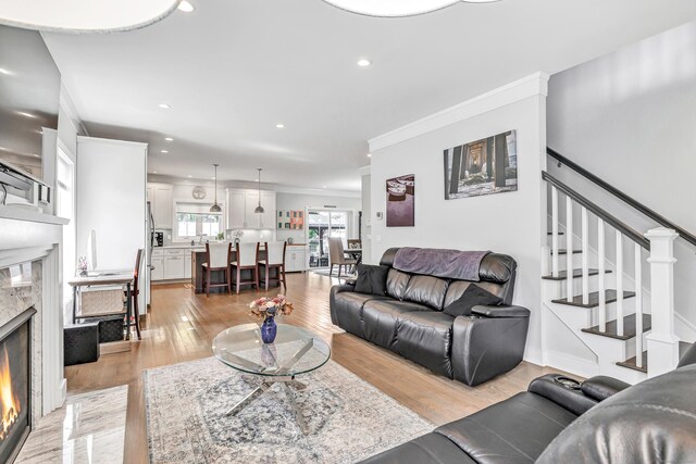 74 Sterling St, Fairfield, CT 06825 - living room featuring light wood-style flooring, recessed lighting, a fireplace, stairway, and crown molding