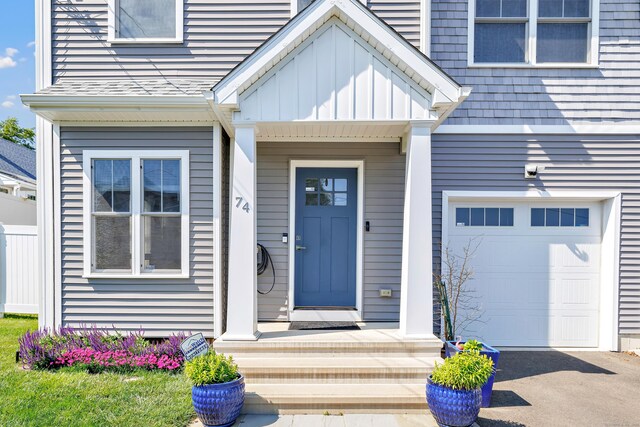 74 Sterling St, Fairfield, CT 06825 - doorway to property featuring a garage, board and batten siding, and driveway