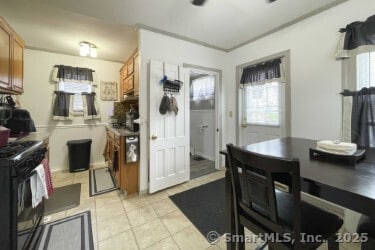 25 Myrtle Ave, Ansonia, CT 06401 - kitchen with brown cabinetry, plenty of natural light, black gas range, and light tile patterned flooring