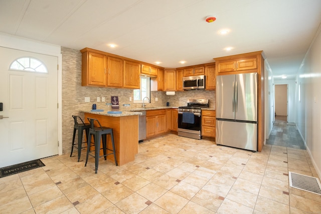 45 Twin Oaks Ln, Danbury, CT 06810 - kitchen featuring stainless steel appliances, a sink, light stone countertops, a peninsula, and brown cabinets