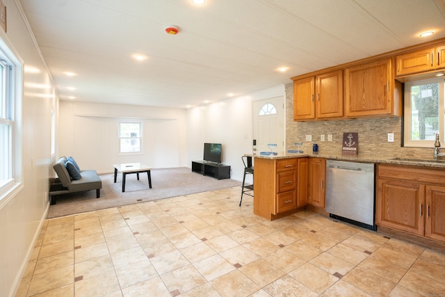 45 Twin Oaks Ln, Danbury, CT 06810 - kitchen featuring stainless steel dishwasher, a sink, open floor plan, light stone counters, and brown cabinets