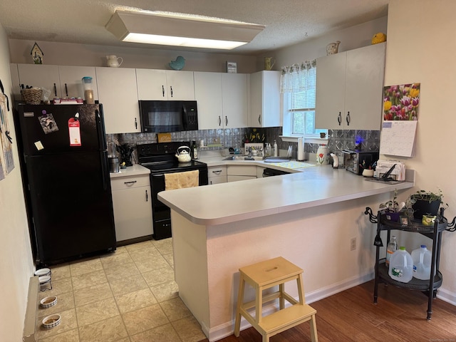 925 Oronoke Rd Unit 26F, Waterbury, CT 06708 - kitchen featuring black appliances, a peninsula, light countertops, backsplash, and a kitchen breakfast bar