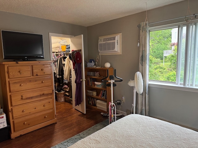 925 Oronoke Rd Unit 26F, Waterbury, CT 06708 - bedroom with wood finished floors, an AC wall unit, a spacious closet, multiple windows, and a textured ceiling