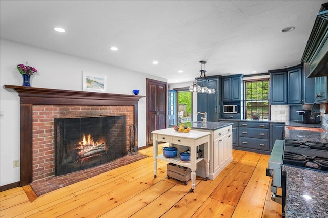 286 Limestone Rd, Ridgefield, CT 06877 - kitchen featuring stainless steel microwave, light wood-type flooring, a fireplace, a kitchen island, and recessed lighting