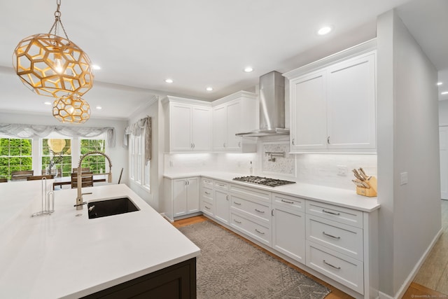41 Leeward Ln, Groton, CT 06340 - kitchen featuring wall chimney range hood, a sink, stainless steel gas stovetop, white cabinetry, and light wood finished floors