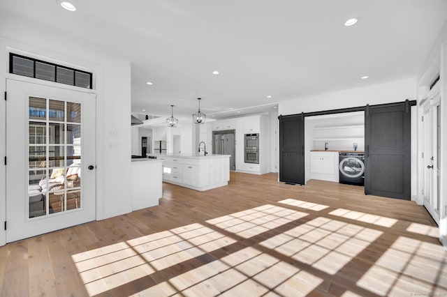19 Cedarbrook Ln, East Lyme, CT 06333 - unfurnished living room with washer / clothes dryer, a barn door, light wood finished floors, and recessed lighting